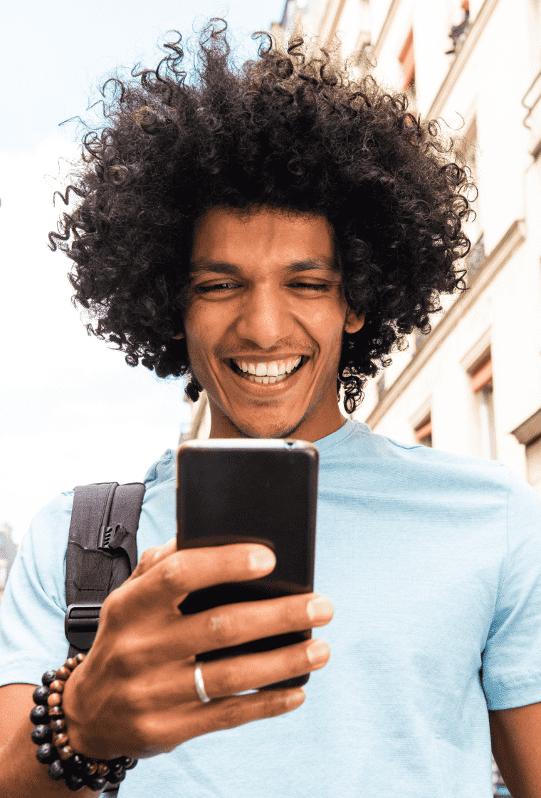 Man walking down street smiling at phone