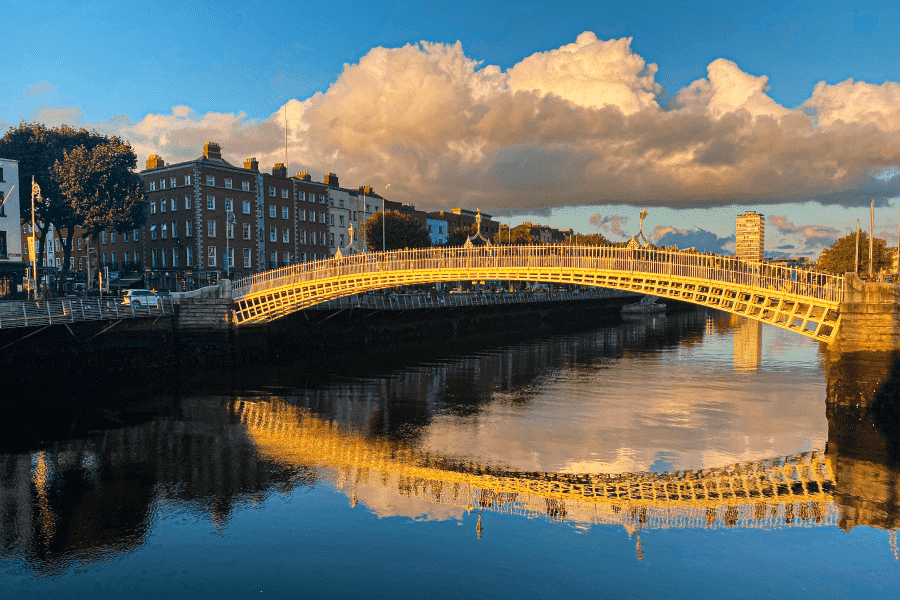 View of Ha Penny Bridge over the Liffey River at sunset in Dublin